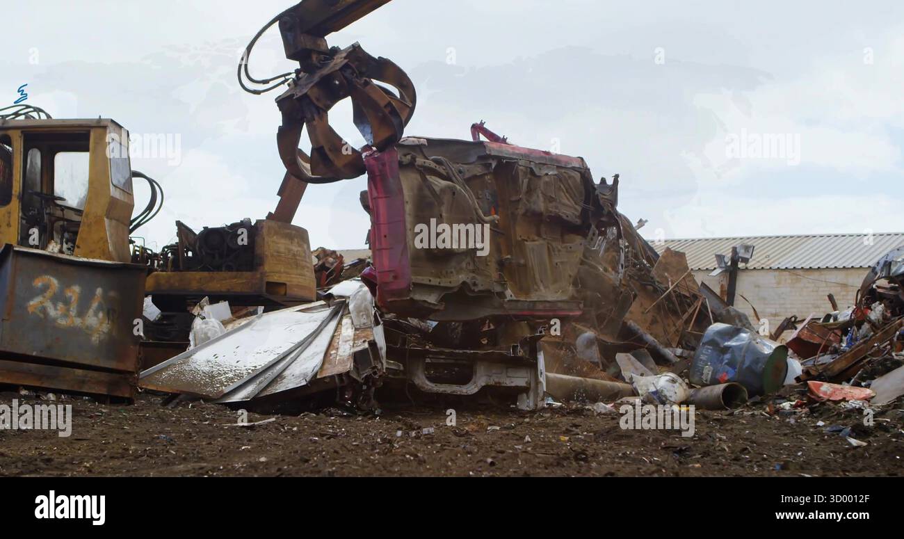 Sollevamento di telai di auto arrugginiti frantumati con gancio meccanico in un terreno di rottami fangoso, con canne Foto Stock