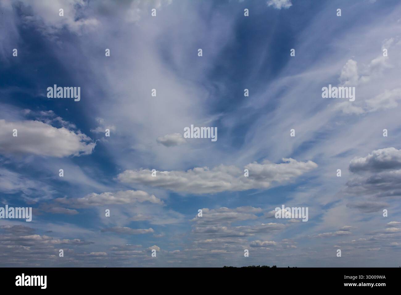 Soffici nuvole bianche attraversano un cielo blu profondo che getta ombre morbide sui campi sottostanti creando un'atmosfera tranquilla perfetta per il relax. Foto Stock