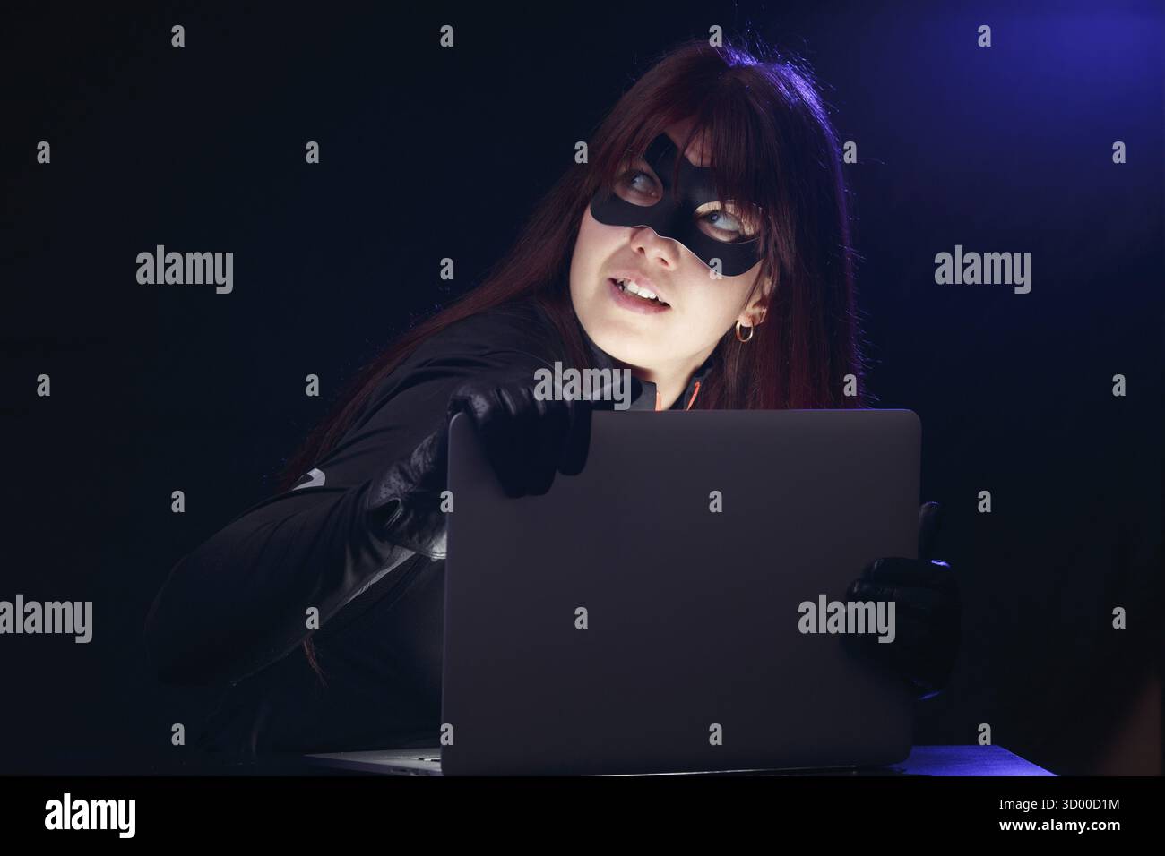 Bruna in maschera con il portatile di notte Foto Stock