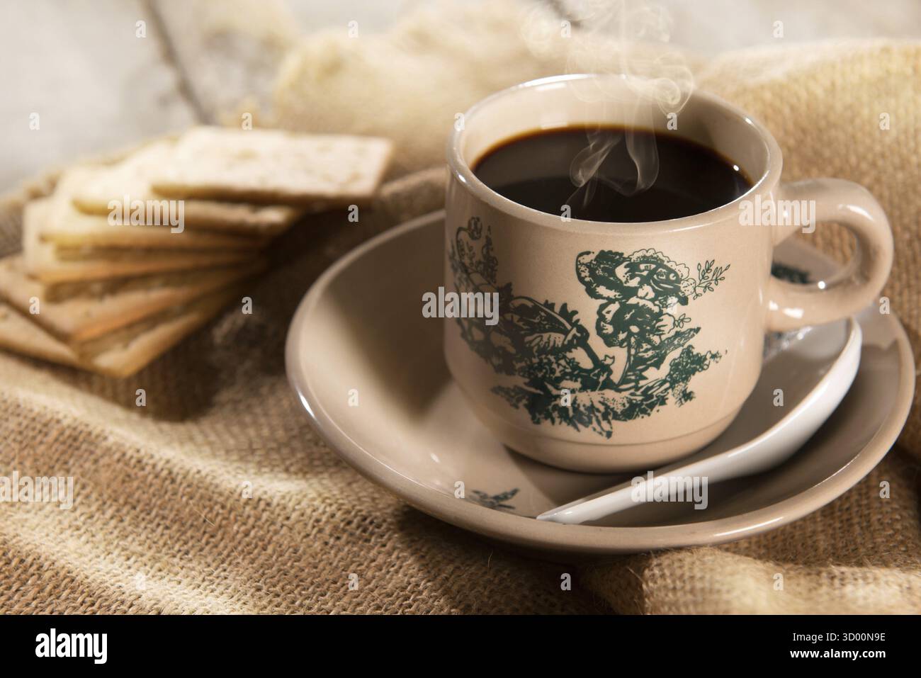 Cuocere a vapore il tradizionale caffè scuro in stile kopitiam cinese orientale in tazze e piattini vintage con cracker soda. Il frattale sulla coppa è una stampa generica. Quindi Foto Stock