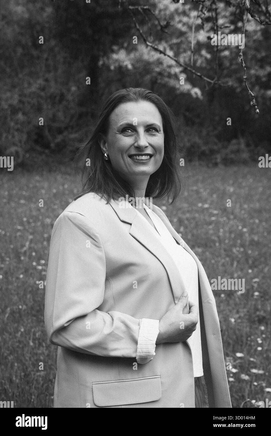 Donna felice di mezza età che ama la natura e si abbraccia nel campo primaverile. Concetto di auto-amore, salute femminile, equilibrio emotivo, consapevolezza, An Foto Stock