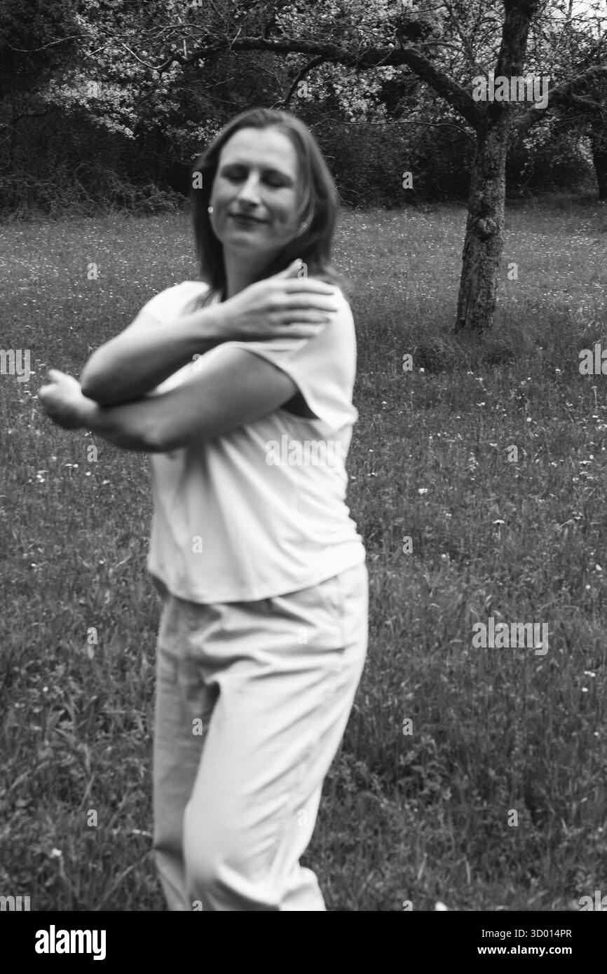 Donna felice di mezza età che ama la natura e si abbraccia nel campo primaverile. Concetto di auto-amore, salute femminile, equilibrio emotivo, consapevolezza, An Foto Stock