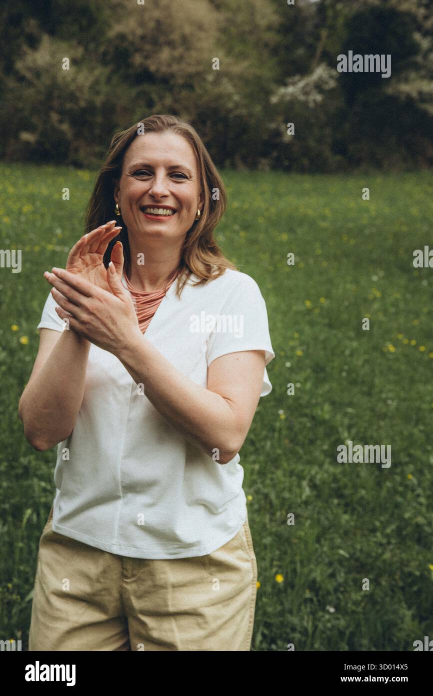 Donna felice di mezza età che ama la natura e si abbraccia nel campo primaverile. Concetto di auto-amore, salute femminile, equilibrio emotivo, consapevolezza, An Foto Stock
