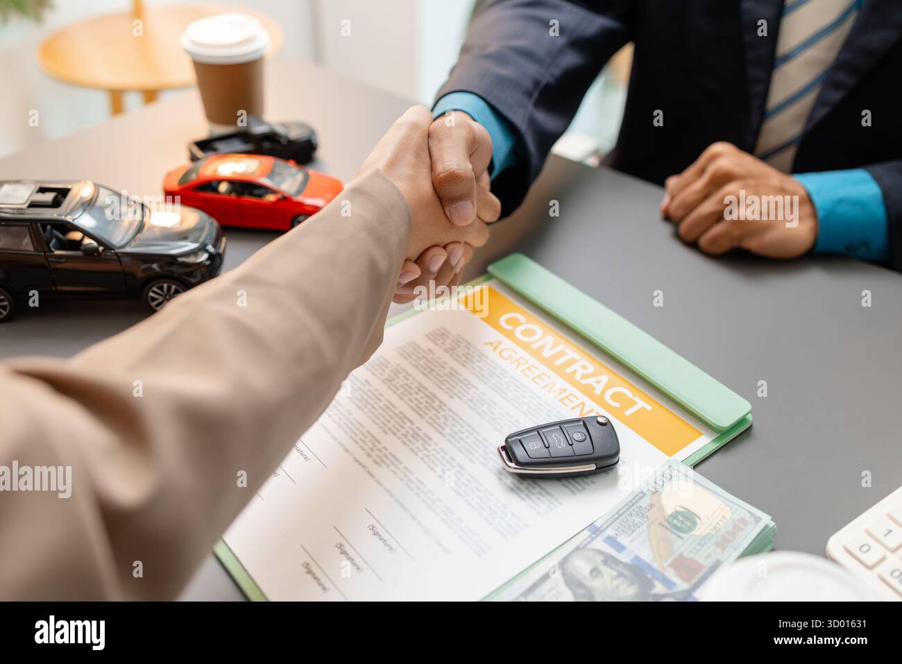 Un rappresentante delle vendite di auto e un cliente stringono la mano dopo aver firmato un contratto di acquisto del veicolo. La stretta di mano riflette soddisfazione, fiducia e successo Foto Stock