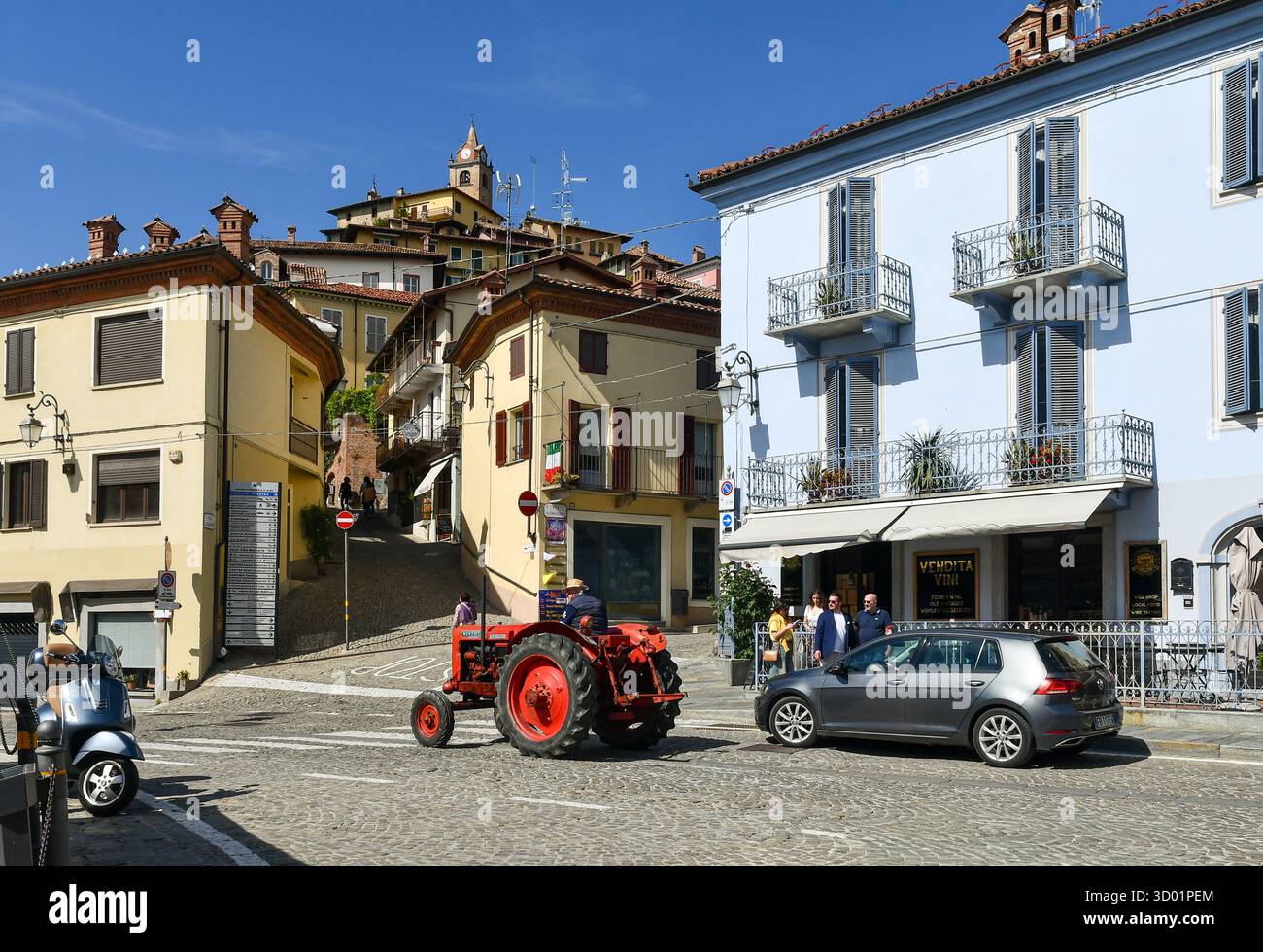 Un trattore d'epoca Nuffield 460 rosso brillante passa nel borgo antico delle colline delle Langhe, Monforte d'Alba (Cuneo), Piemonte, Italia Foto Stock