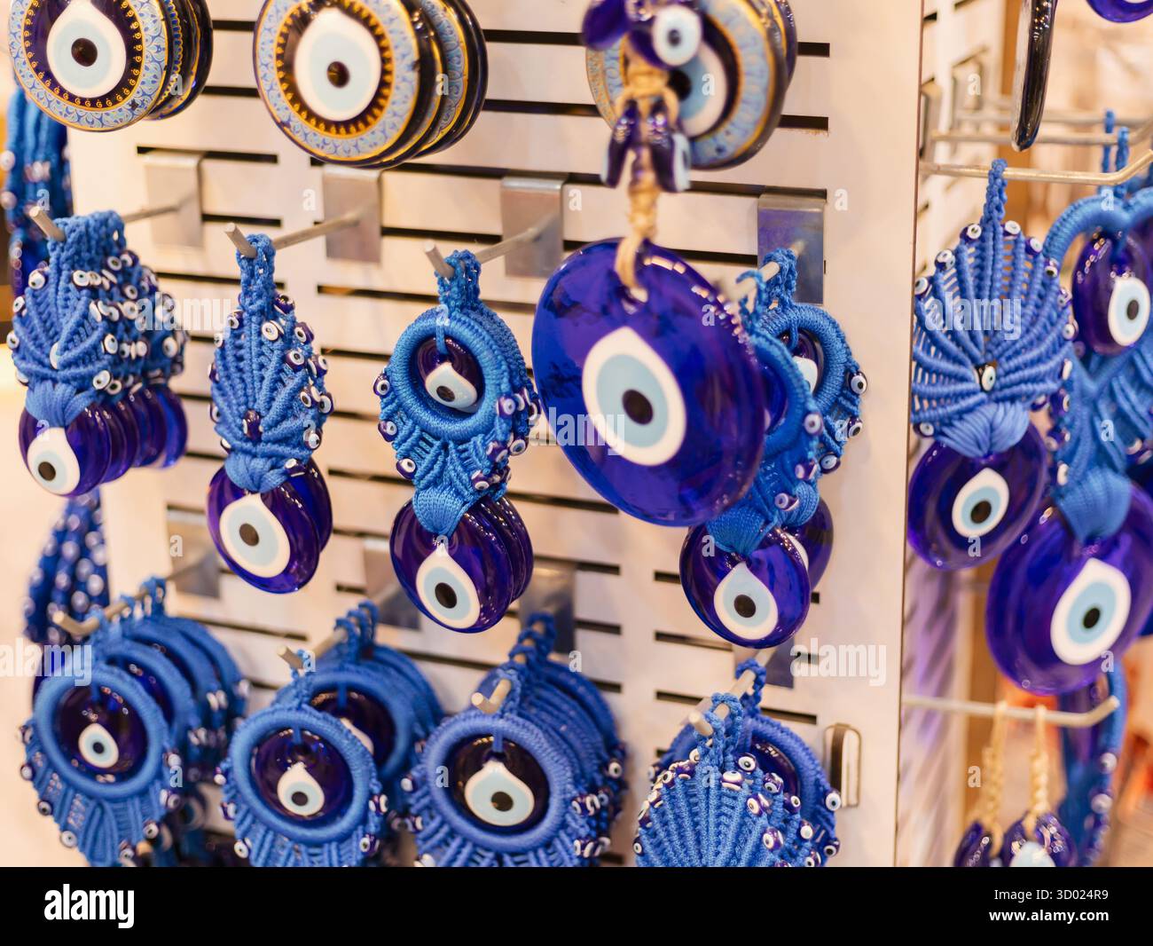 File di ornamenti in vetro blu per occhio malvagio sono appese su un espositore. Ogni ornamento presenta un design unico e riflette la luce, creando una visua accattivante Foto Stock