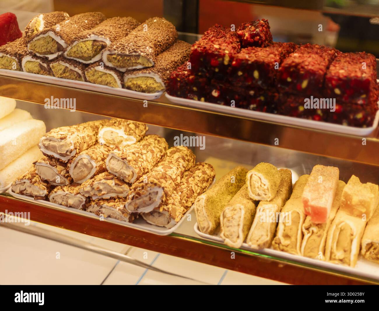 Un vivace spettacolo di dolci tradizionali con una varietà di texture e colori. La vetrina include dolci e cubetti arrotolati, invitanti custo Foto Stock
