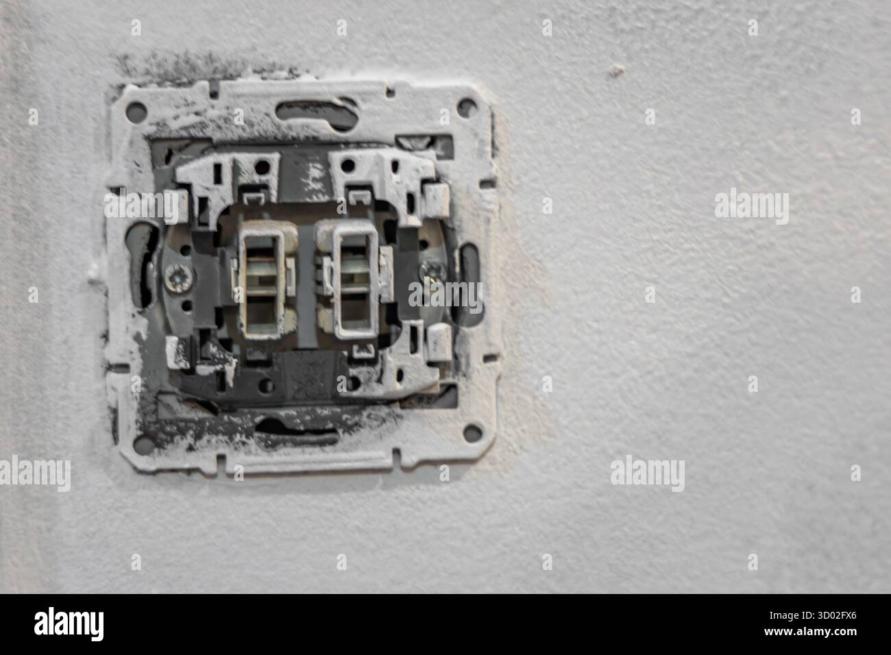 Primo piano del cablaggio dell'interruttore della luce elettrica smontato senza piastra di copertura sulla parete durante la ristrutturazione della casa. Concetto di riparazione e manutenzione di elettricità, Foto Stock