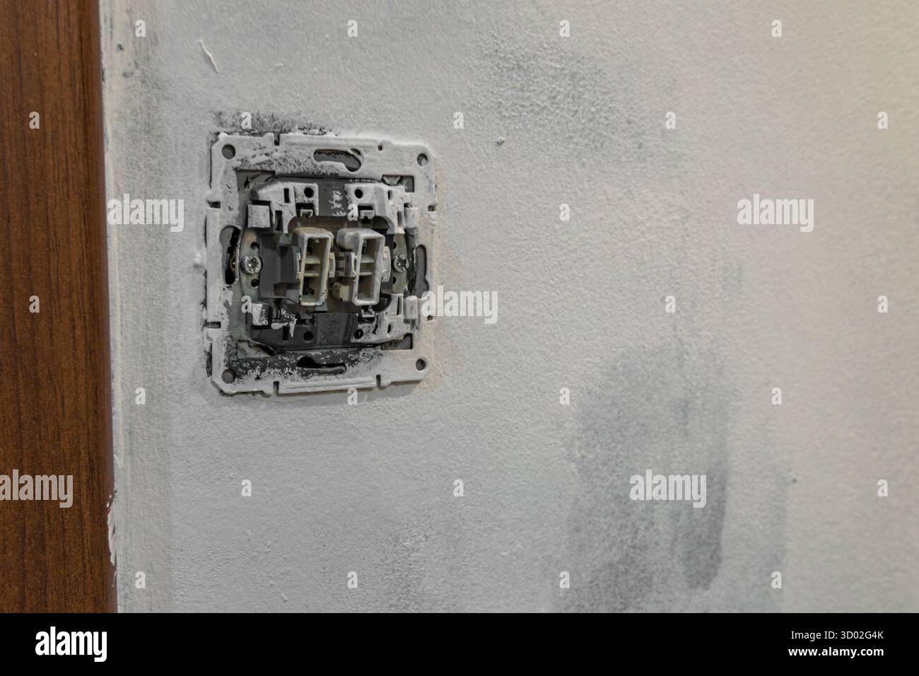 Primo piano del cablaggio dell'interruttore della luce elettrica smontato senza piastra di copertura sulla parete durante la ristrutturazione della casa. Concetto di riparazione e manutenzione di elettricità, Foto Stock