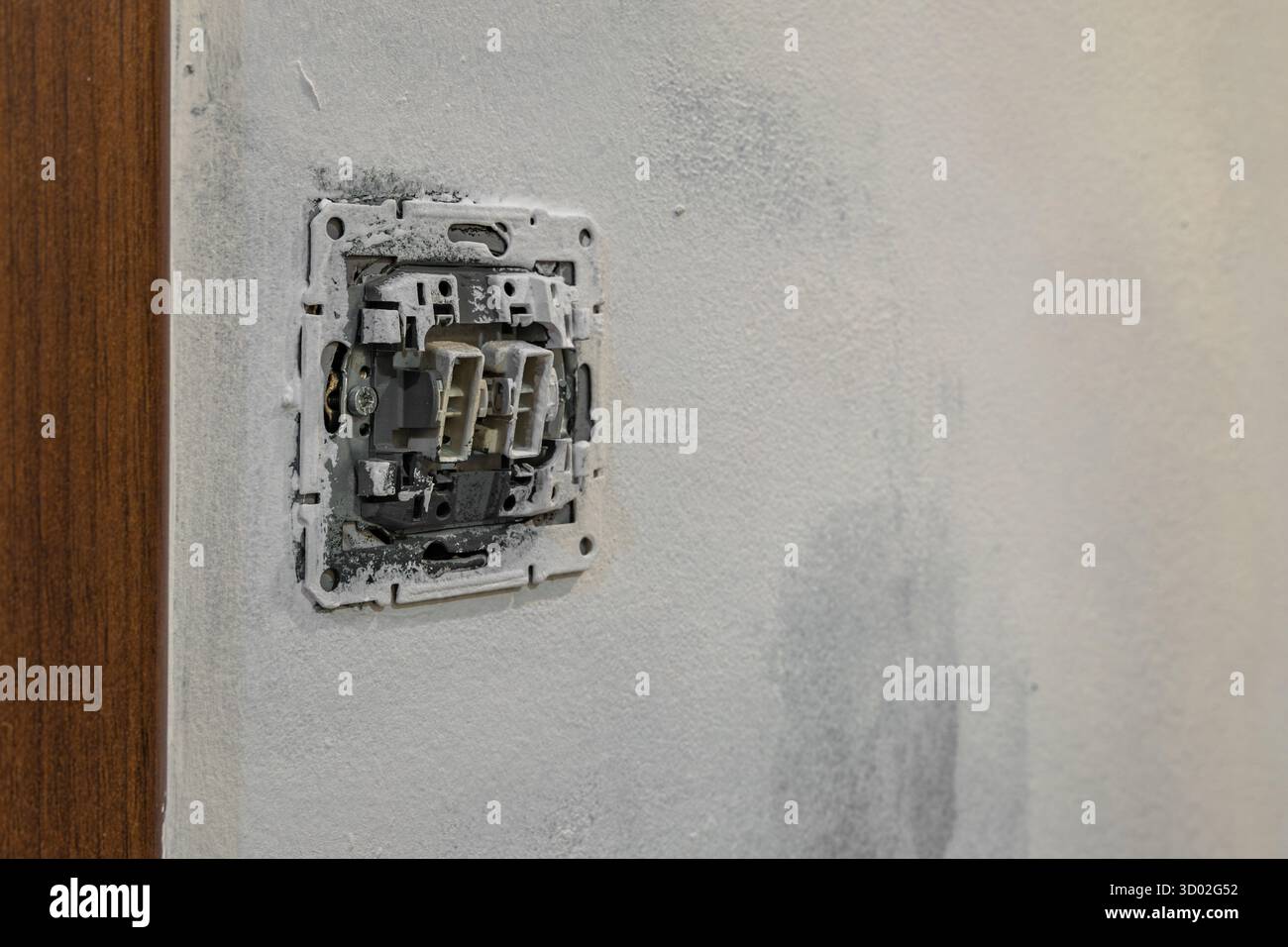 Primo piano del cablaggio dell'interruttore della luce elettrica smontato senza piastra di copertura sulla parete durante la ristrutturazione della casa. Concetto di riparazione e manutenzione di elettricità, Foto Stock