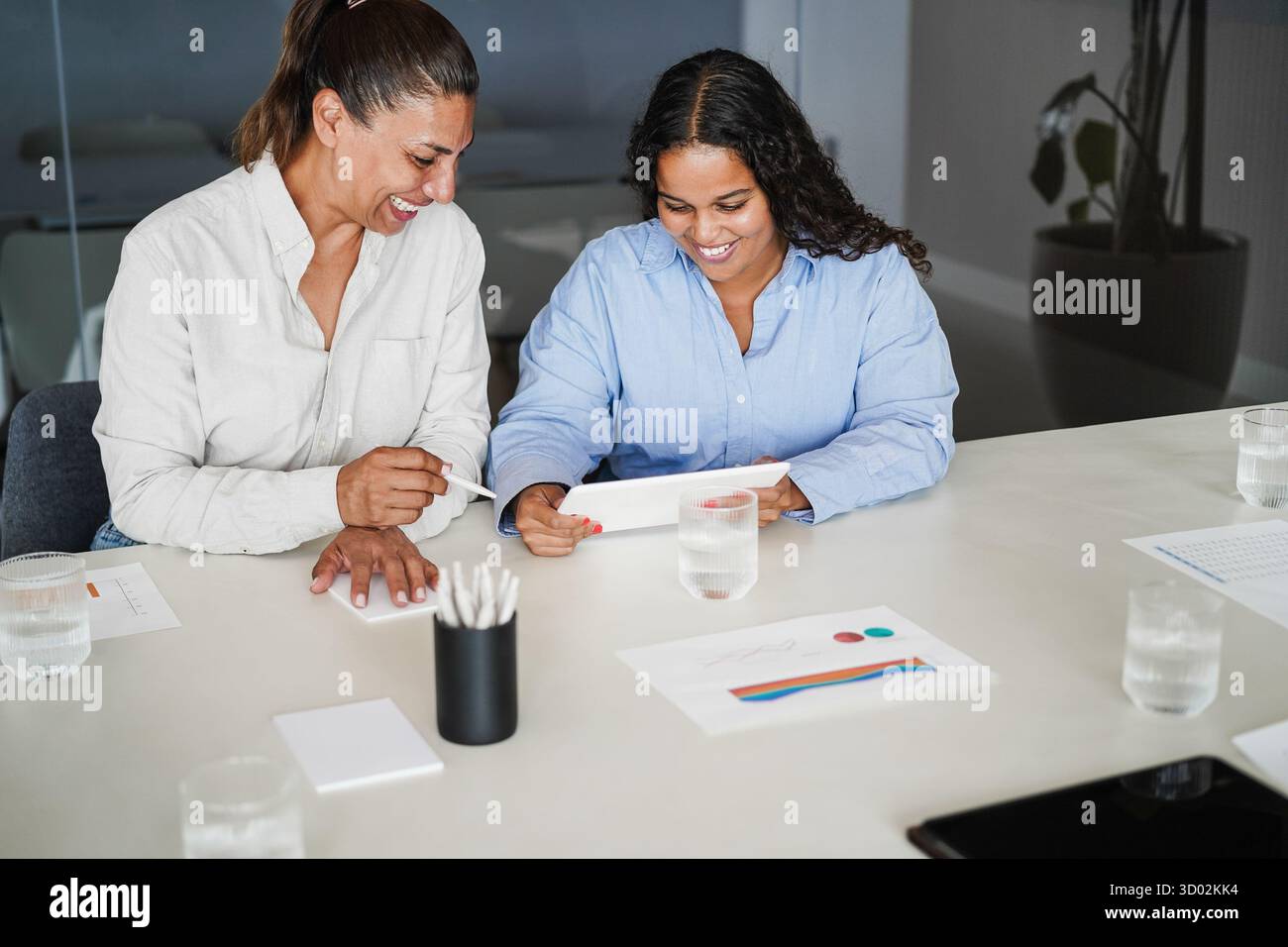 Donne d'affari che condividono idee all'interno dell'ufficio aziendale - colleghi latini donne che discutono di un nuovo progetto finanziario Foto Stock