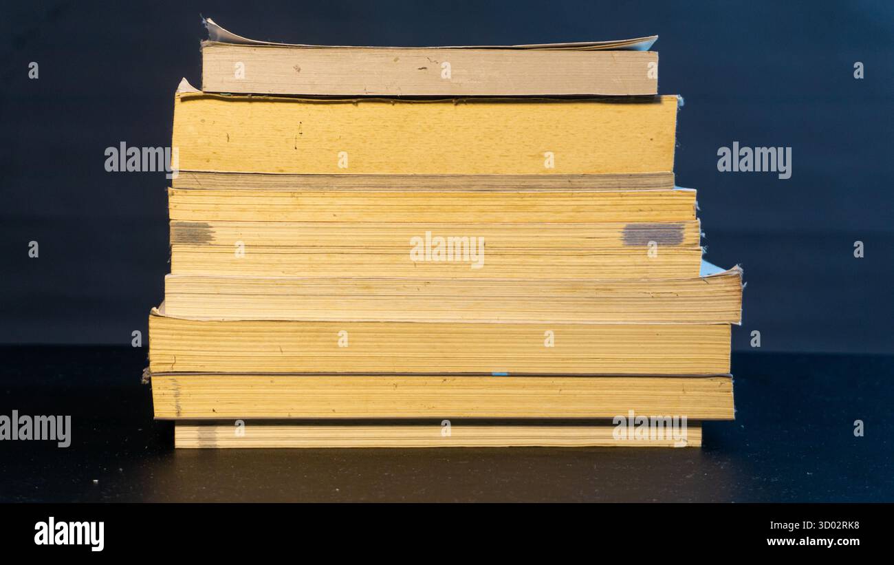 Libri ordinatamente impilati su sfondo nero, composizione pulita e organizzata con un concetto accademico, educativo o editoriale minimale Foto Stock