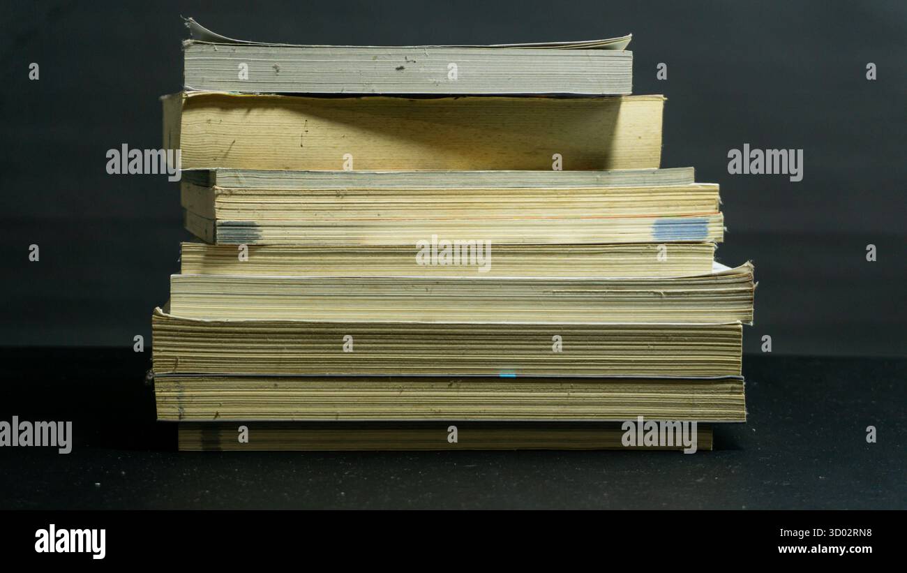 Libri ordinatamente impilati su sfondo nero, composizione pulita e organizzata con un concetto accademico, educativo o editoriale minimale Foto Stock