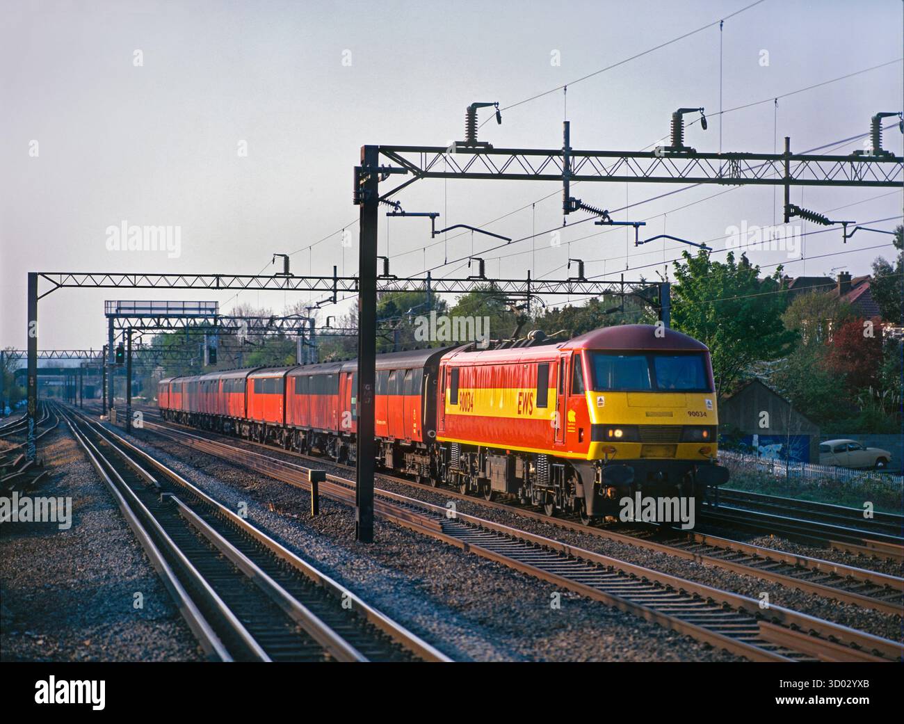Una locomotiva elettrica di classe 90 n. 90034 che opera su un treno di furgoni postali lungo la West Coast Mainline a South Kenton il 23 aprile 2003. Foto Stock Una locomotiva elettrica di classe 90 n. 90034 che opera su un treno di furgoni postali lungo la West Coast Mainline a South Kenton il 23 aprile 2003. Foto Stock