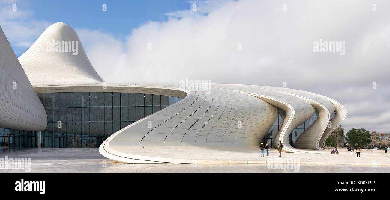 Baku, Azerbaigian - 7 maggio 2024: Heydar Aliyev Center. Iconica architettura moderna con linee bianche fluenti e facciata in vetro sotto un cielo nuvoloso. Gente sulla piazza Foto Stock