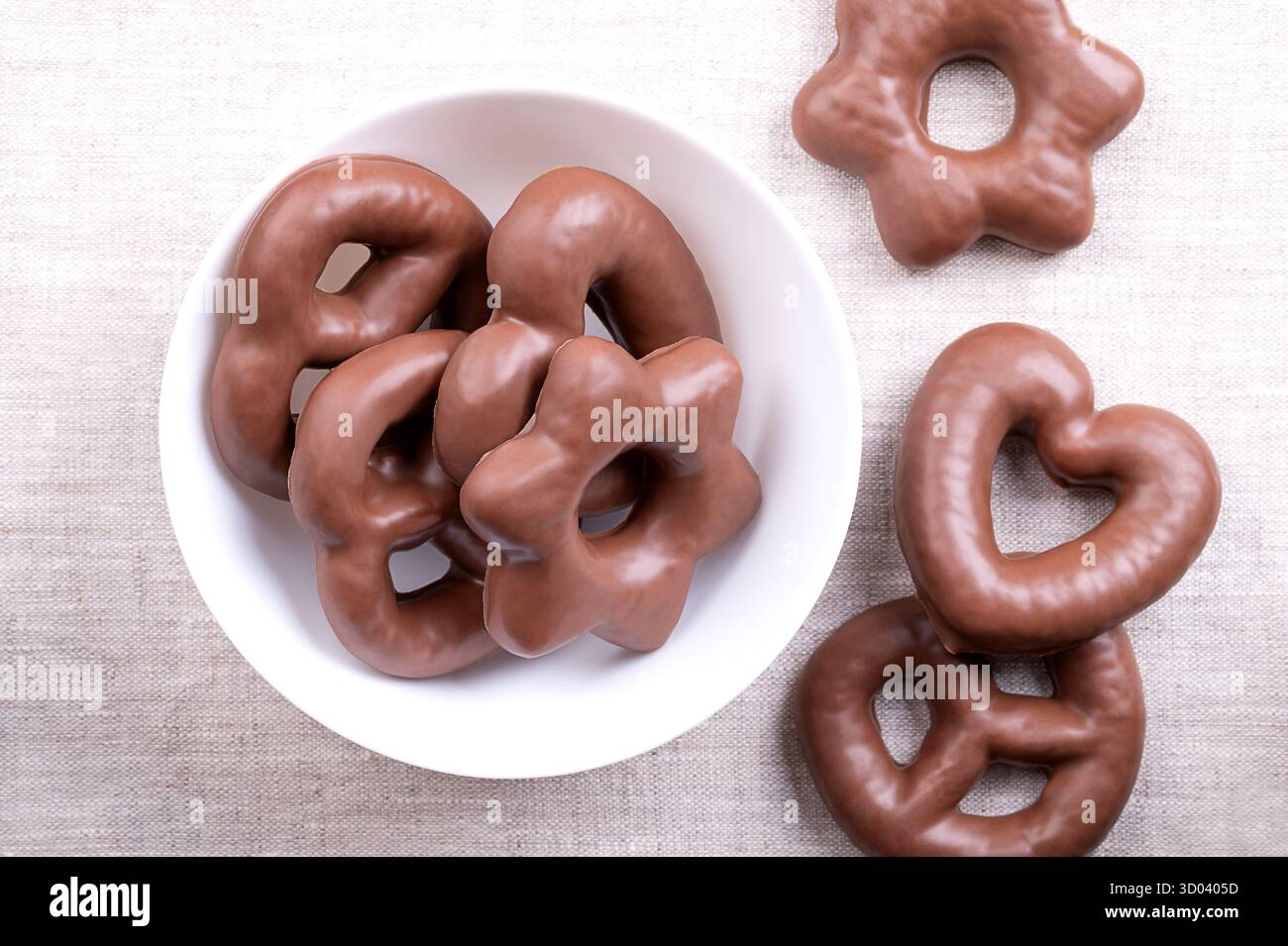 Pan di zenzero ricoperto di cioccolato, in un recipiente bianco, su lino. Lebkuchen tedesco tradizionale a forma di cuore e stella, completamente ricoperto di cioccolato al latte. Foto Stock