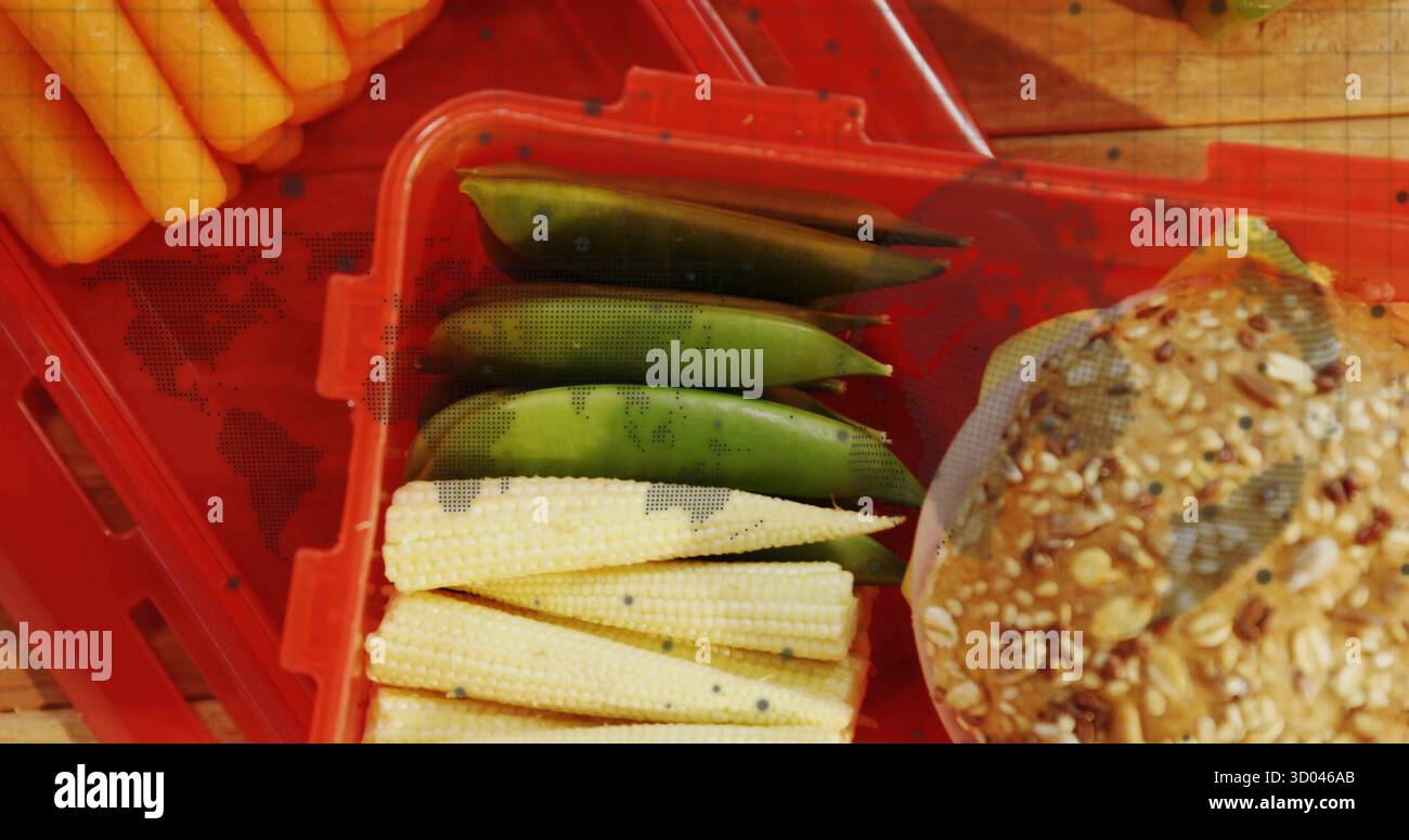 Una cassa rossa che poggia su un piano di lavoro della cucina, contenente mais per bambini, piselli con zucchero e panino di grano seminato Foto Stock