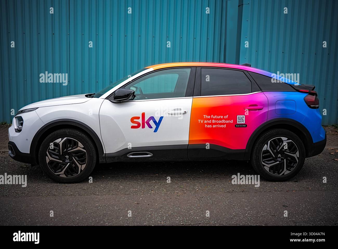 Manchester, Regno Unito, 18 ottobre 2025: Auto colorata che promuove Sky TV e servizi a banda larga parcheggiata da un muro blu. Foto Stock