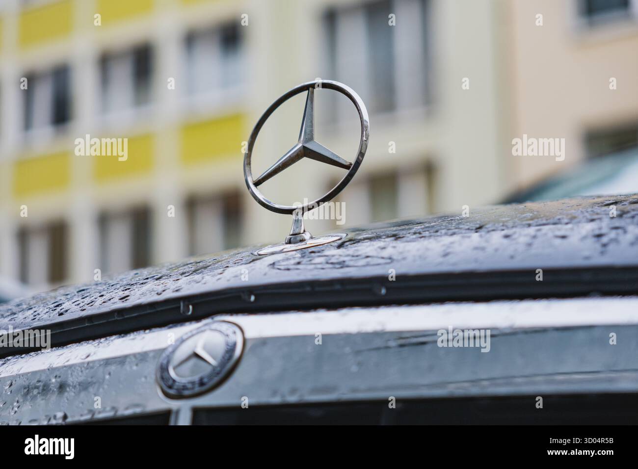Logo Mercedes-Benz a stella a tre punte sulla parte anteriore di un'auto parcheggiata su una strada Foto Stock