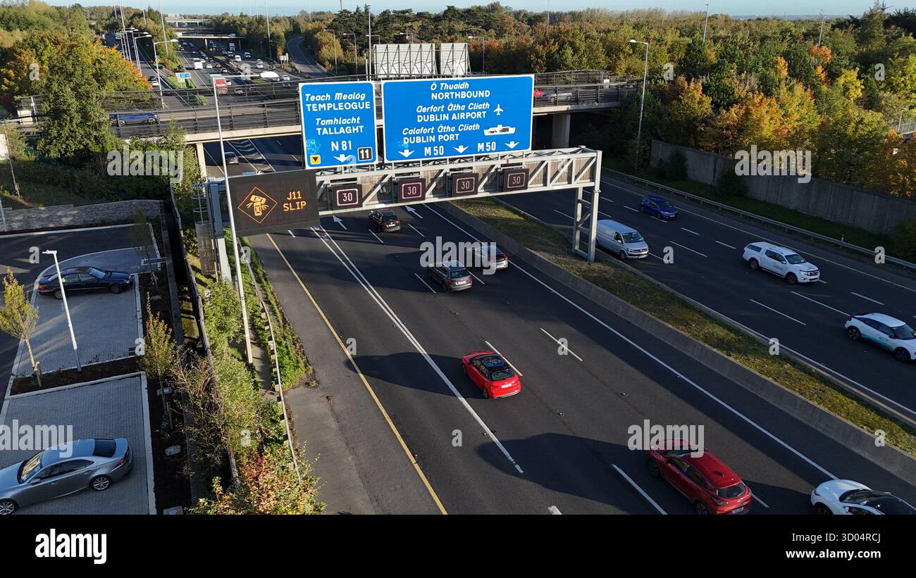 Dublino, Irlanda - 06 ottobre 2025 - immagine aerea del sole che splende sul traffico mattutino della M50 con segnali digitali di limite di velocità variabile visibili Foto Stock