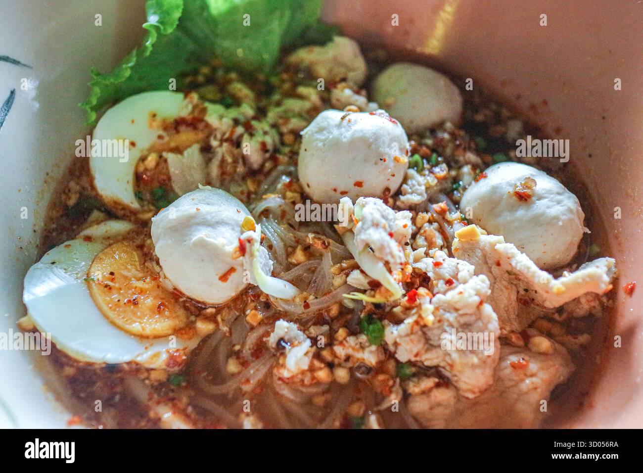 Zuppa di noodle tailandese Tom Yum piccante con maiale, polpette, uova e pasta di peperoncino. Autentico cibo di strada, ricco sapore ed essenziale pasto asiatico. Foto Stock