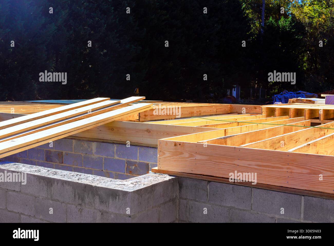 Travi in legno poggiano su fondamenta in calcestruzzo, indicando la costruzione attiva in zona residenziale. Foto Stock
