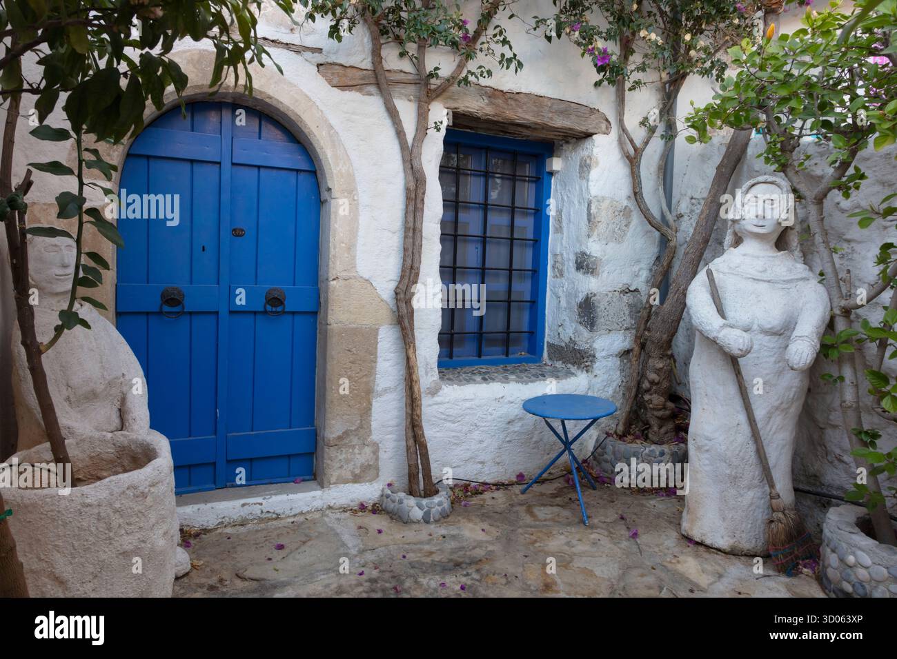 Casa con una porta blu e scultura di una persona a Kritsa, uno dei villaggi più antichi e pittoreschi di Creta, la Grecia Foto Stock