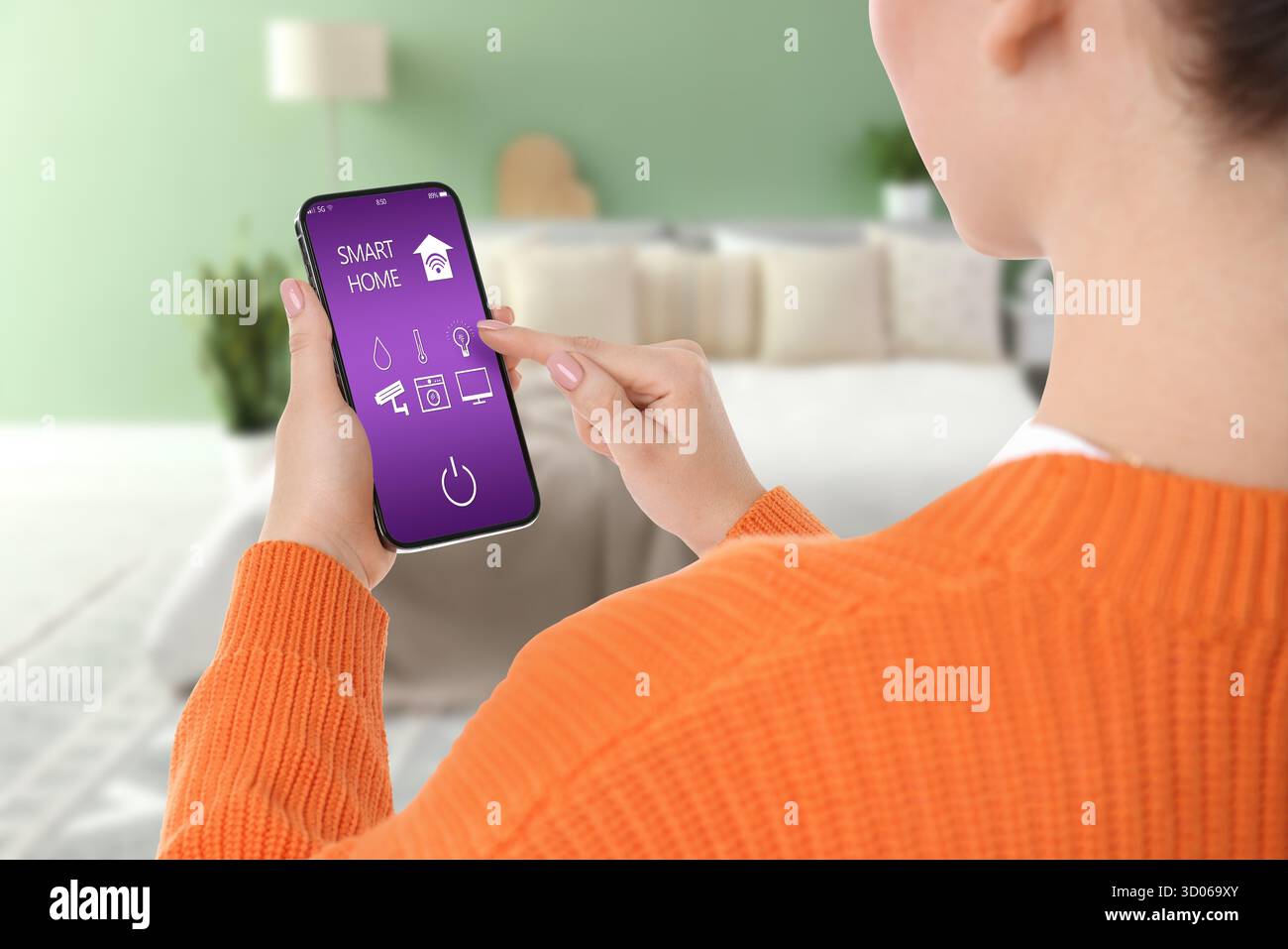 Donna che usa l'app smart home sul cellulare per controllare le funzioni della casa e per primo piano Foto Stock