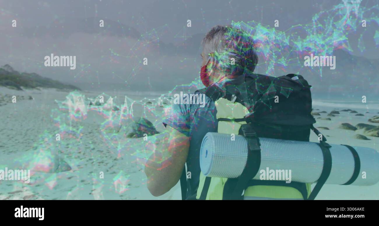 Regolazione delle cinghie dello zaino, escursionista maturo che indossa un rivestimento facciale sulla spiaggia costiera rocciosa, con tappetino in schiuma Foto Stock