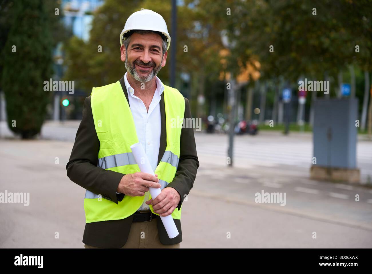 Architetto sorridente che tiene i progetti in strada urbana Foto Stock