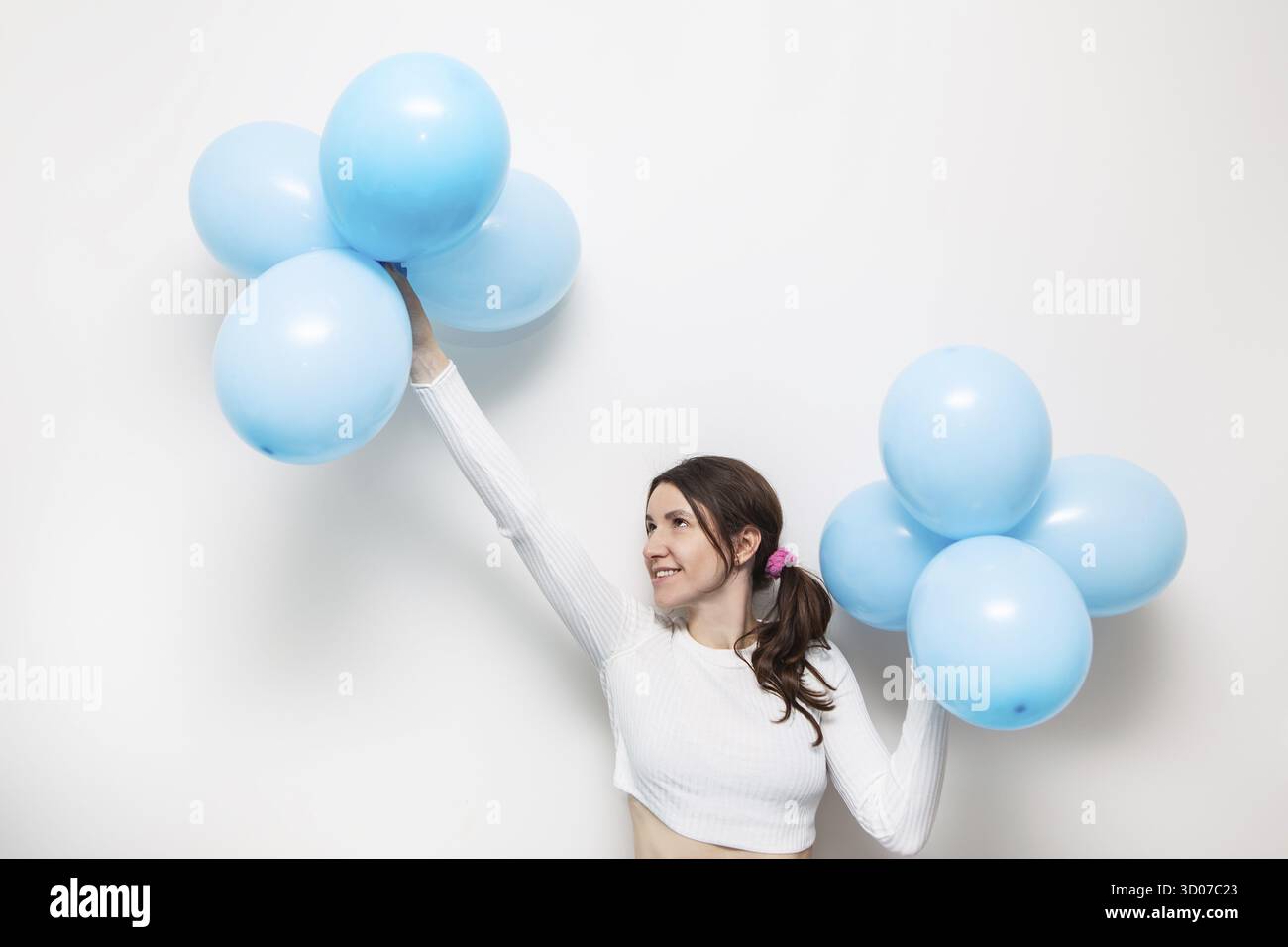 La ragazza felice sorride e tiene palloncini d'aria blu nelle sue mani. Posto per un'iscrizione, concetto di vacanza. Compleanno Foto Stock