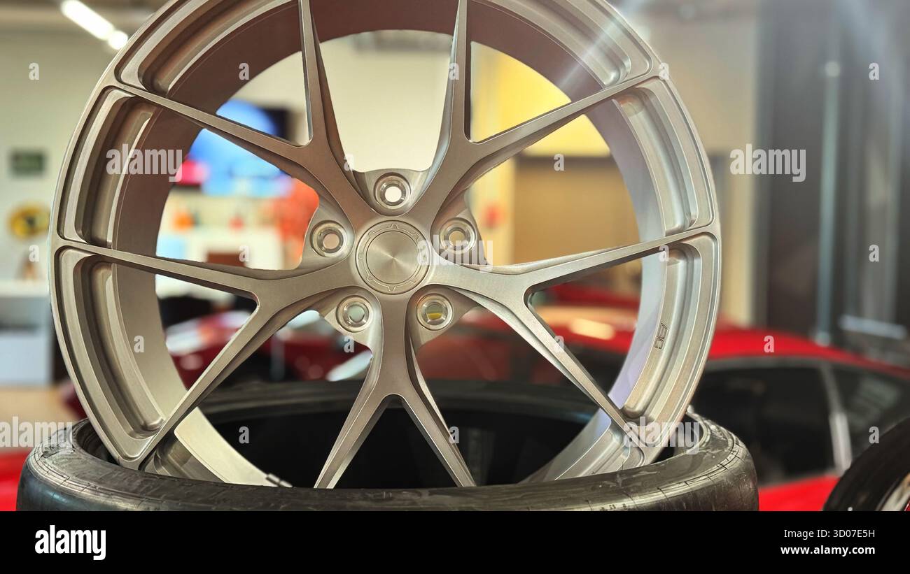 Cerchi in lega d'argento su pneumatici, primo piano sul cerchione per auto moderne, esposizione di officine automobilistiche, dettaglio tecnico di precisione, accessorio per veicoli di lusso, metallo lucido - Immagine stock catturata con smartphone