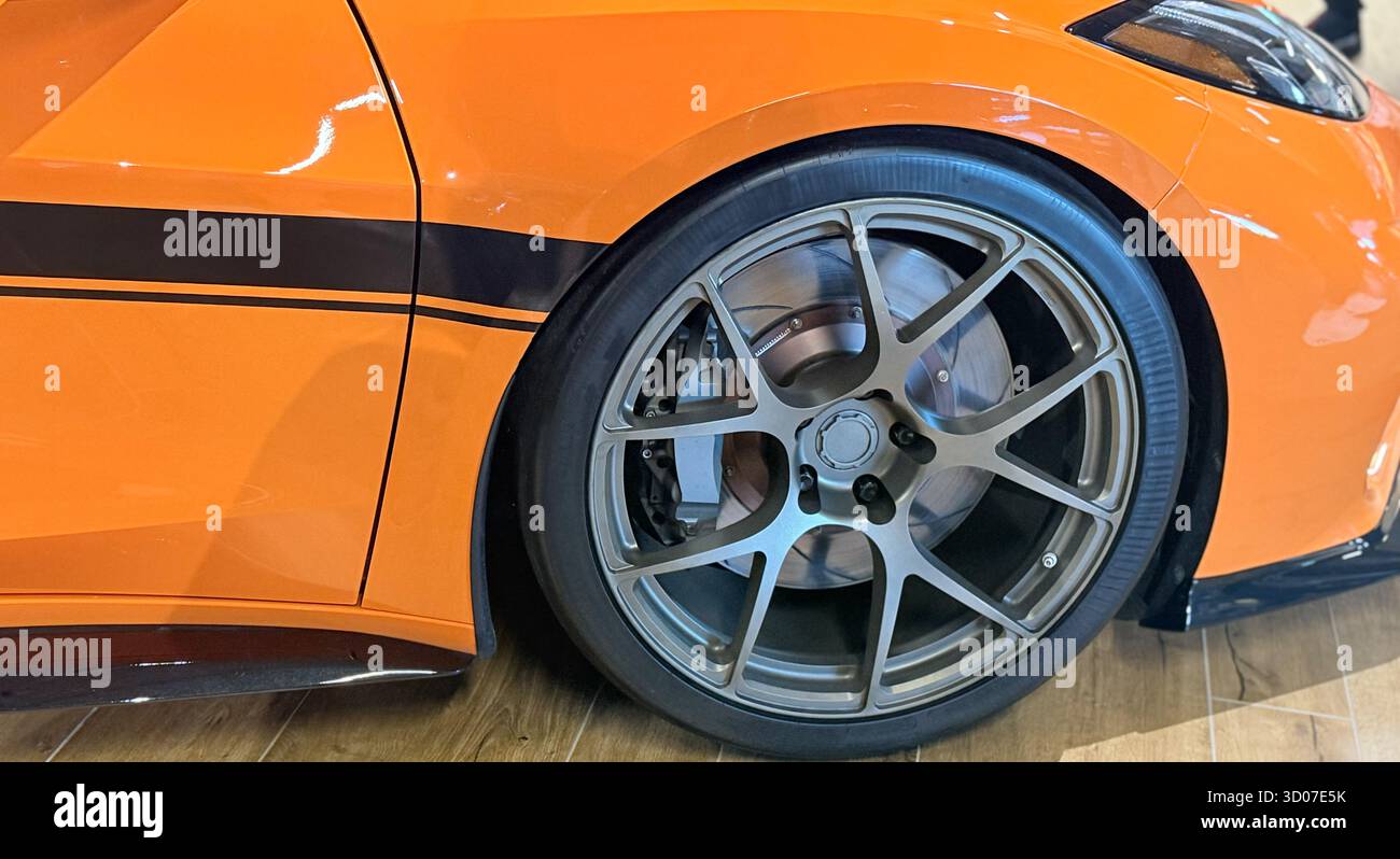 Moderno profilo laterale arancione per auto sportive con cerchi e pneumatici in lega personalizzati. Cerchi in alluminio di alta qualità, dettagli dei freni a disco e concept di ottimizzazione per auto di lusso - Immagine stock catturata con smartphone