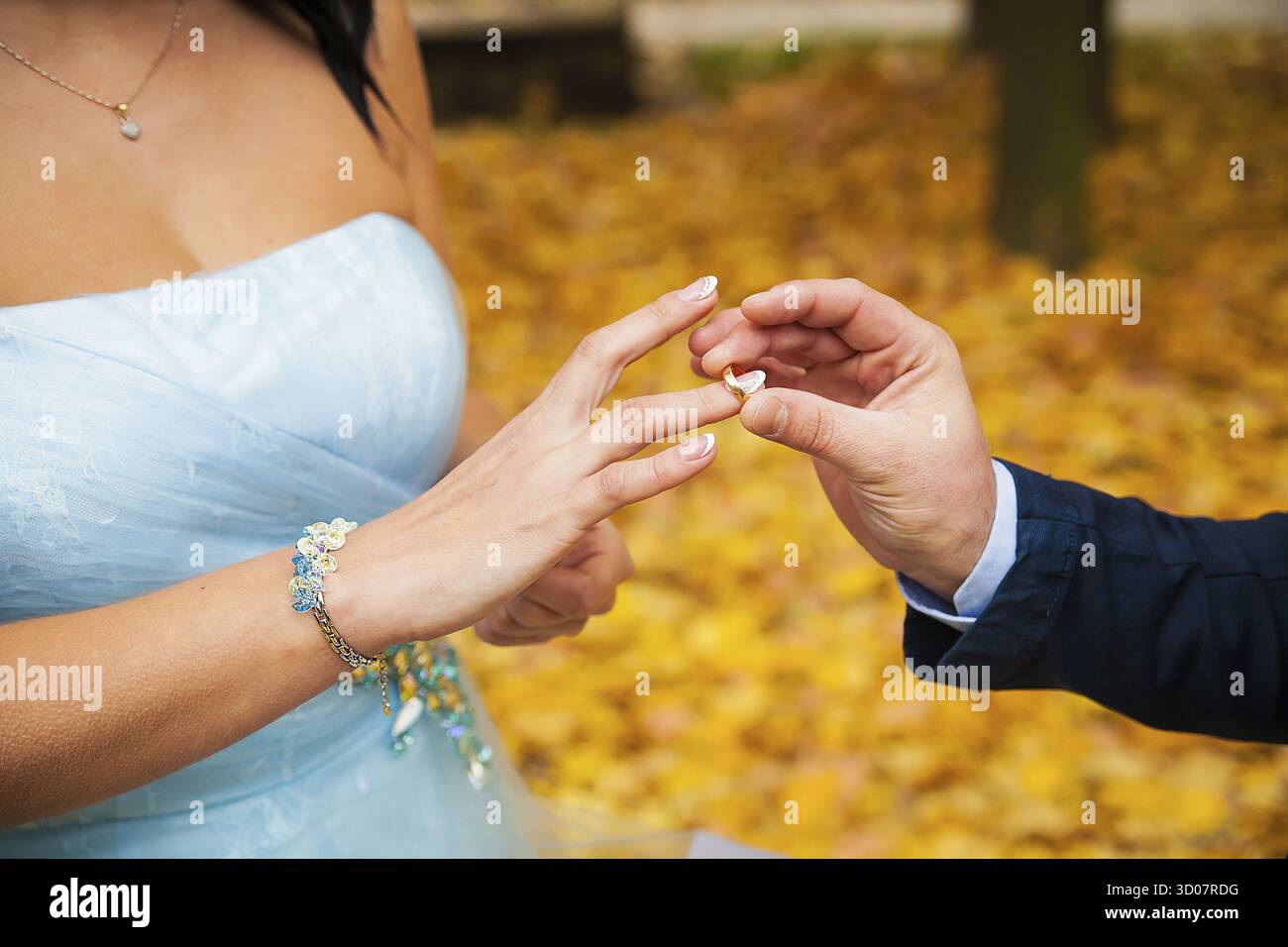 La mano dello sposo che mette un anello nuziale sul dito della sposa Foto Stock