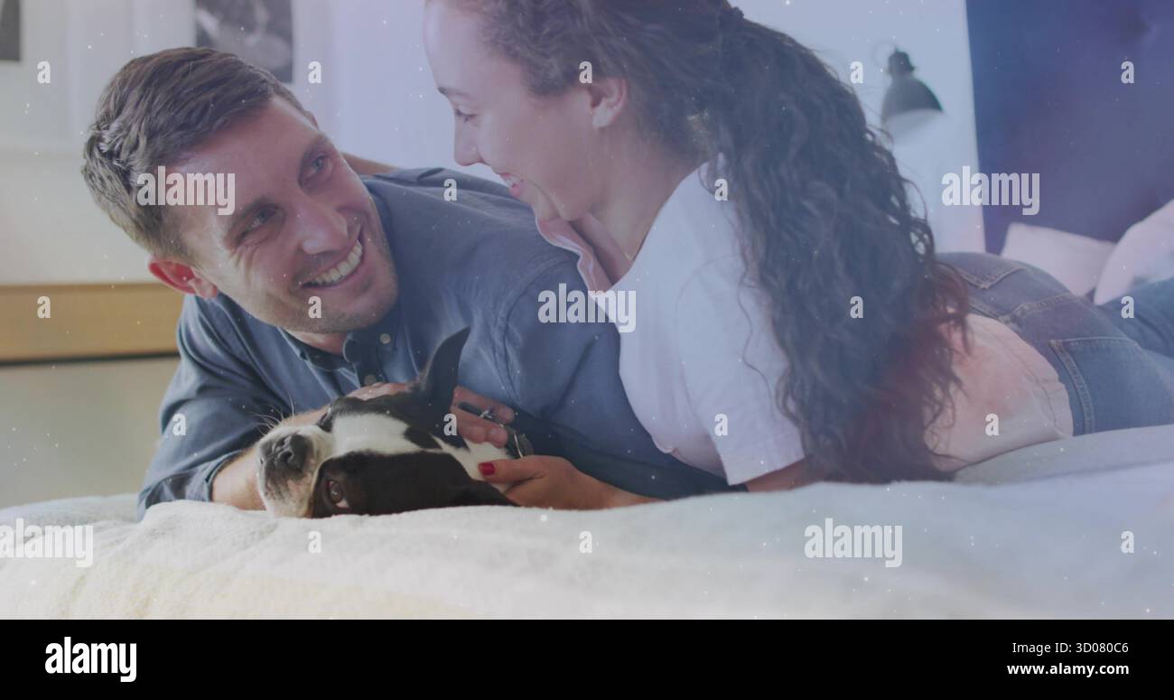 La coppia interagisce si affaccia sul letto con biancheria da letto leggera in camera da letto, incluso un cane bianco e nero Foto Stock
