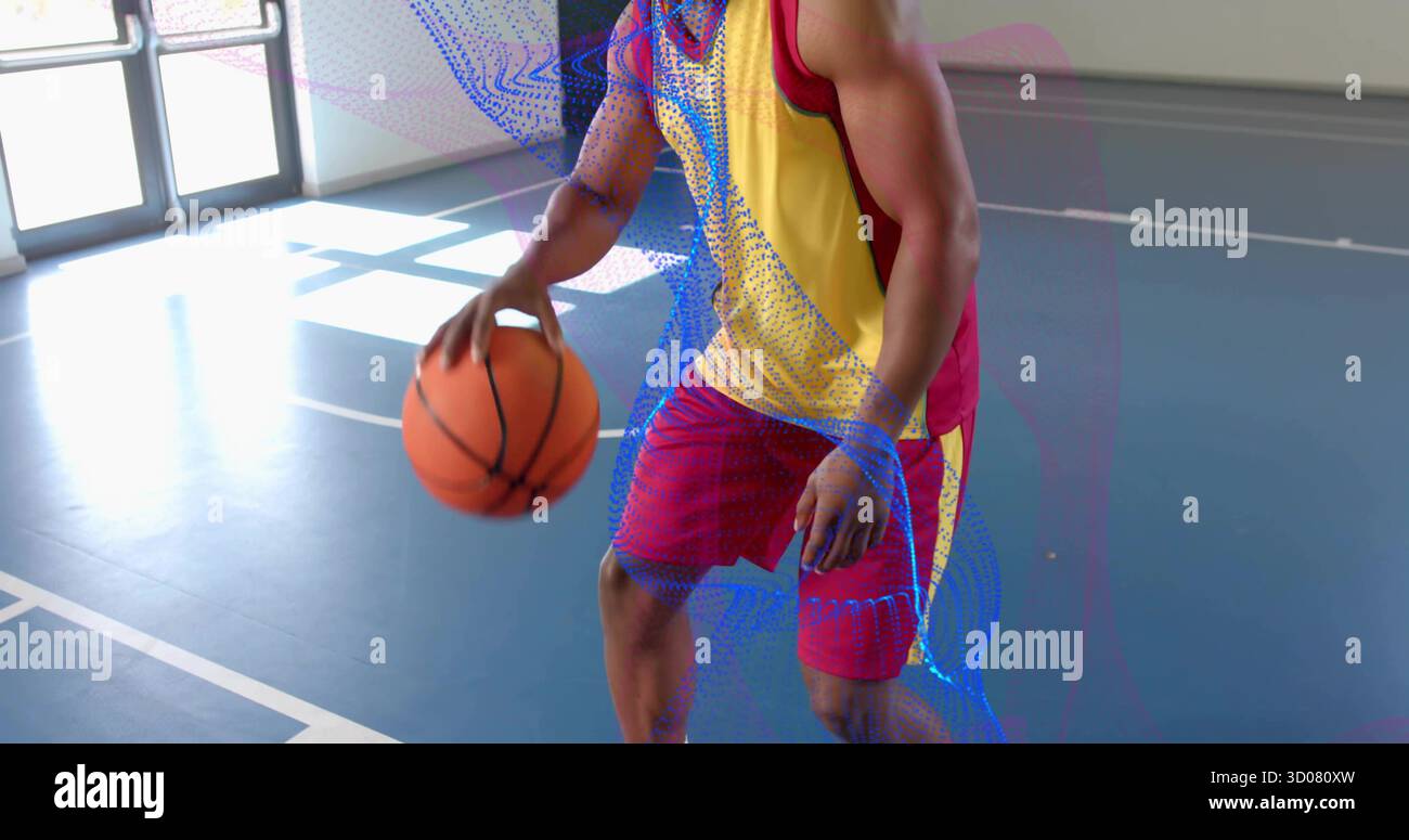 Dribbling man in divisa sportiva gialla rossa sul campo da palestra, con pallacanestro, marcature e porta in vetro Foto Stock