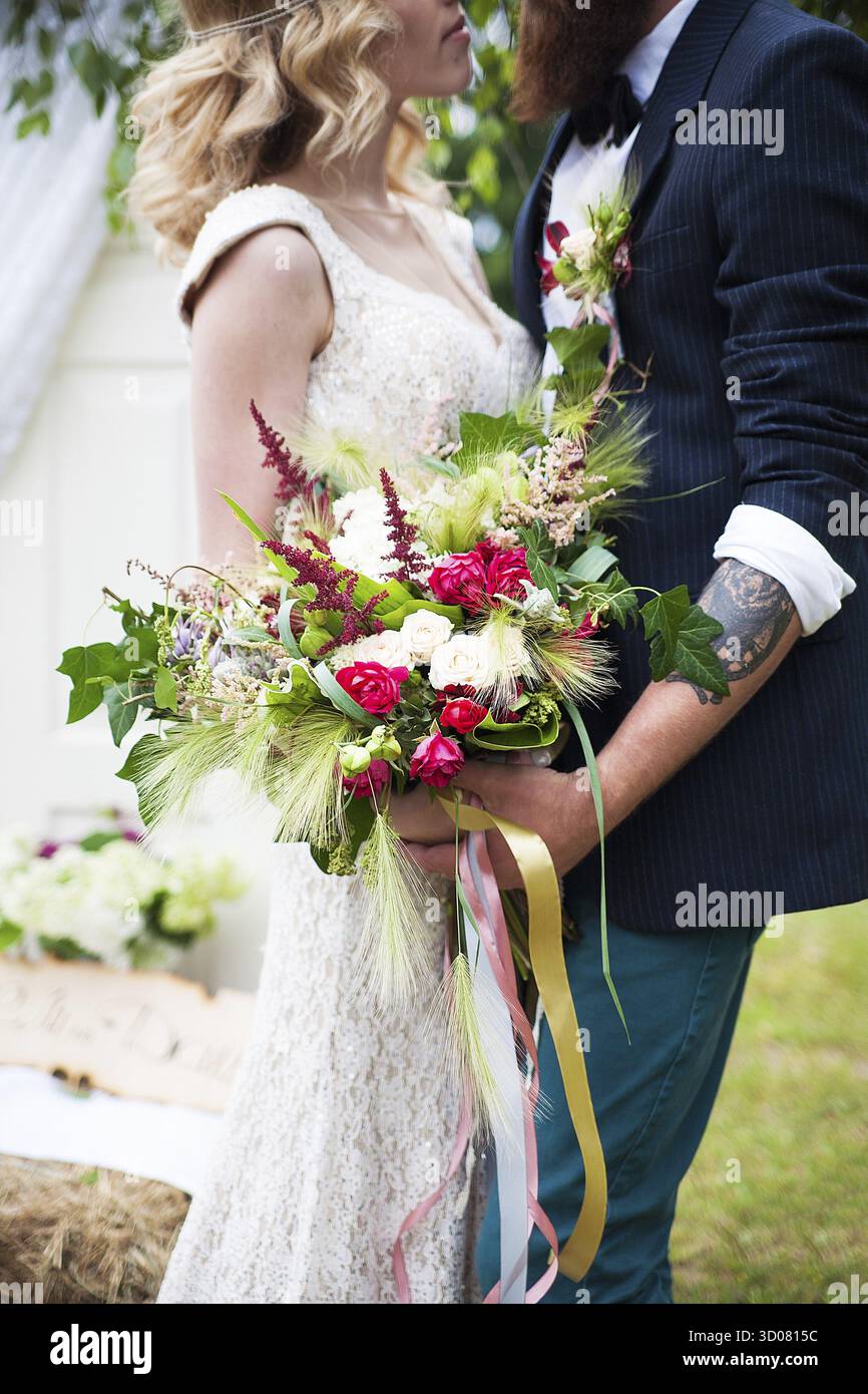 Ragazzo con una camicia bianca e una ragazza con un abito da sposa bianco con bouquet di fiori Foto Stock