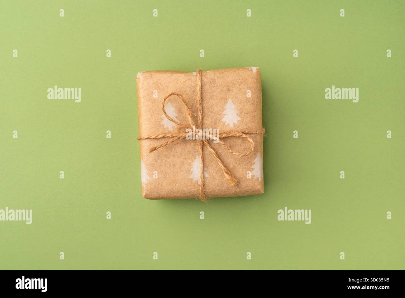 Un regalo di Natale confezionato in una confezione ecologica su sfondo verde Foto Stock
