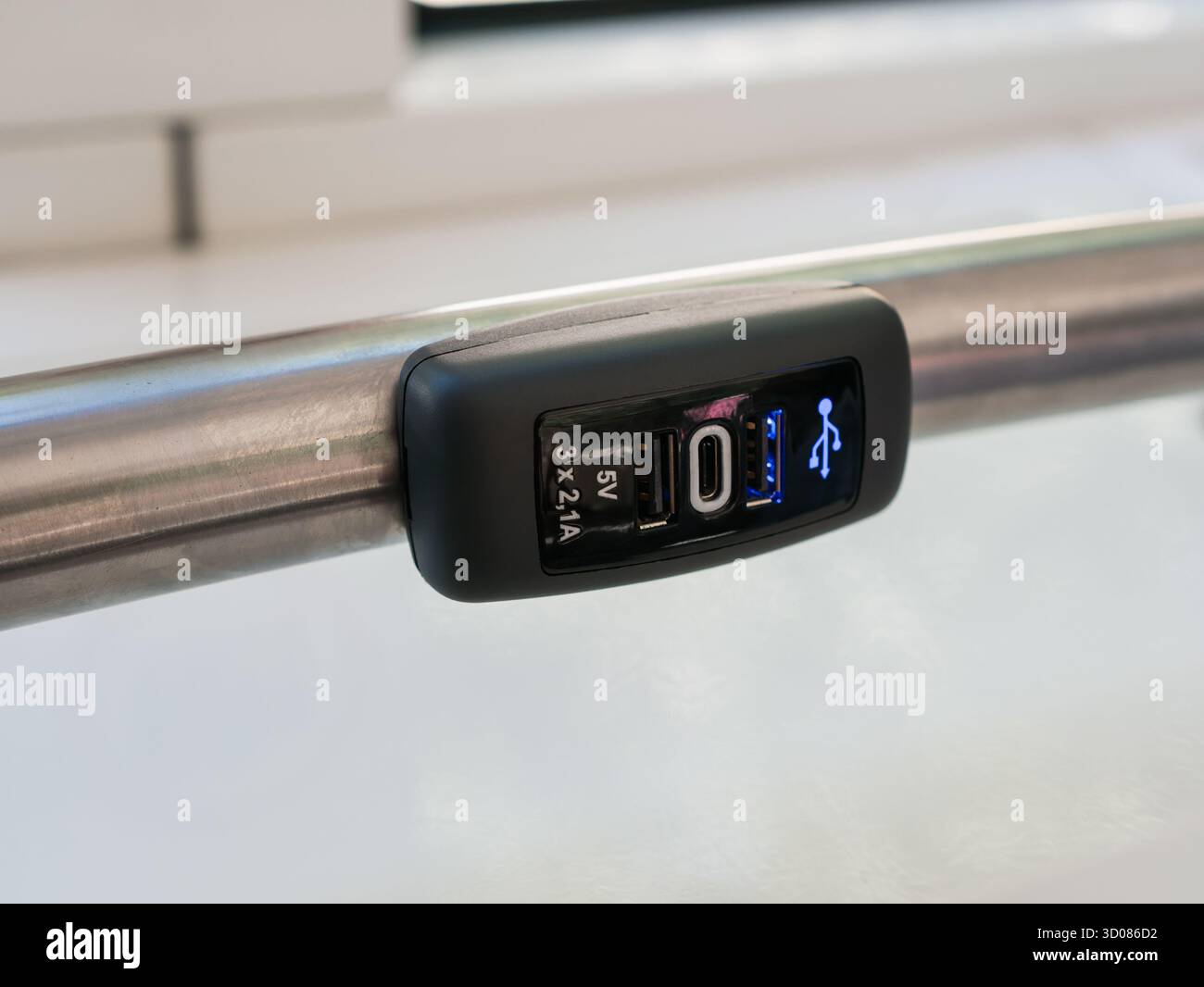 Una presa USB Type-A e Type-C da 5 V per la ricarica degli smartphone, fissata su un corrimano all'interno di un autobus o treno, per la comodità dei passeggeri Foto Stock