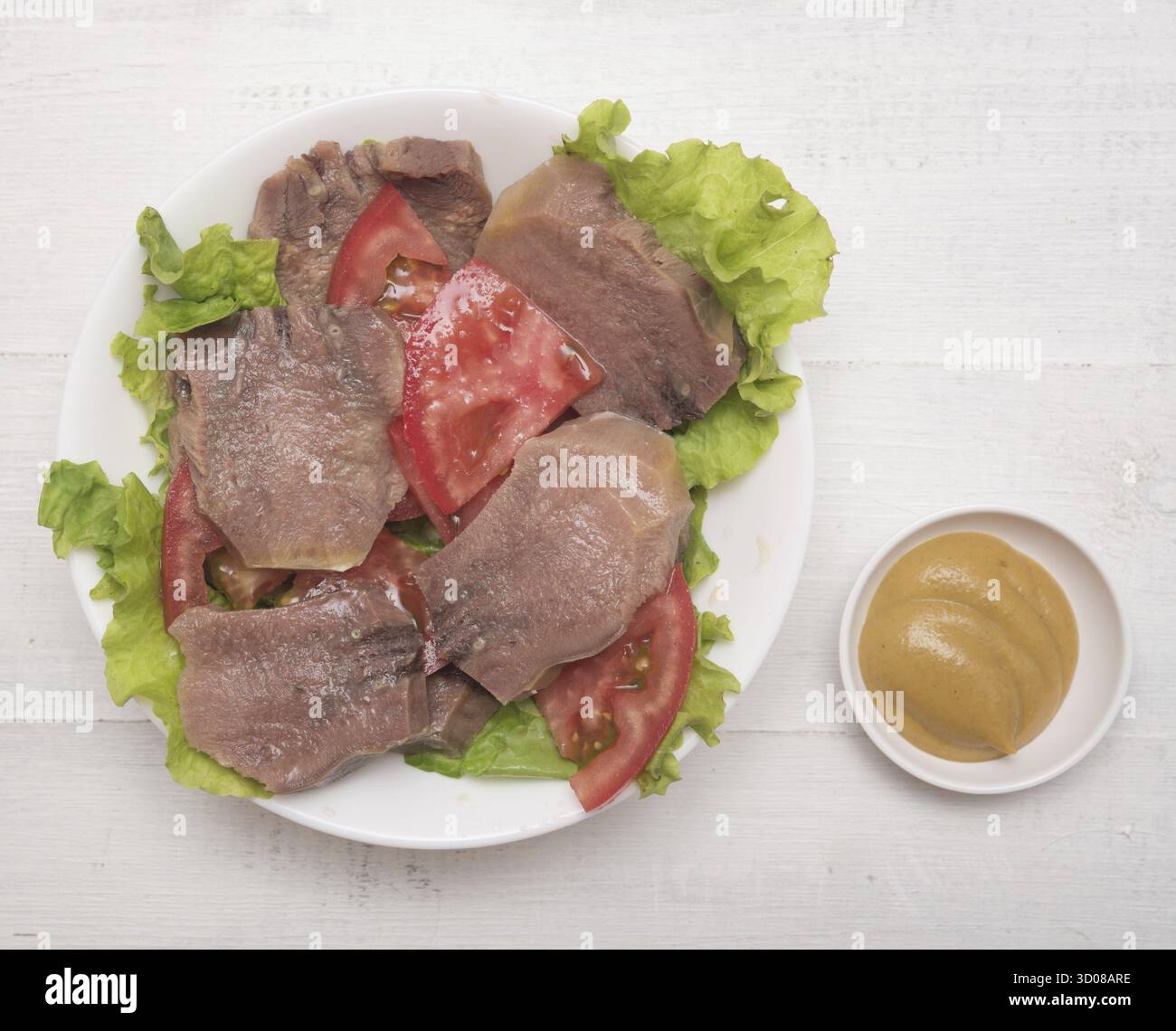Fette di lingua di manzo con pomodoro e senape su sfondo di legno Foto Stock