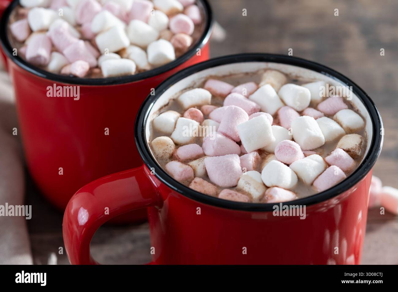 Bevanda calda a base di cioccolata con marshmallow in tazza rossa su un tavolo di legno Foto Stock