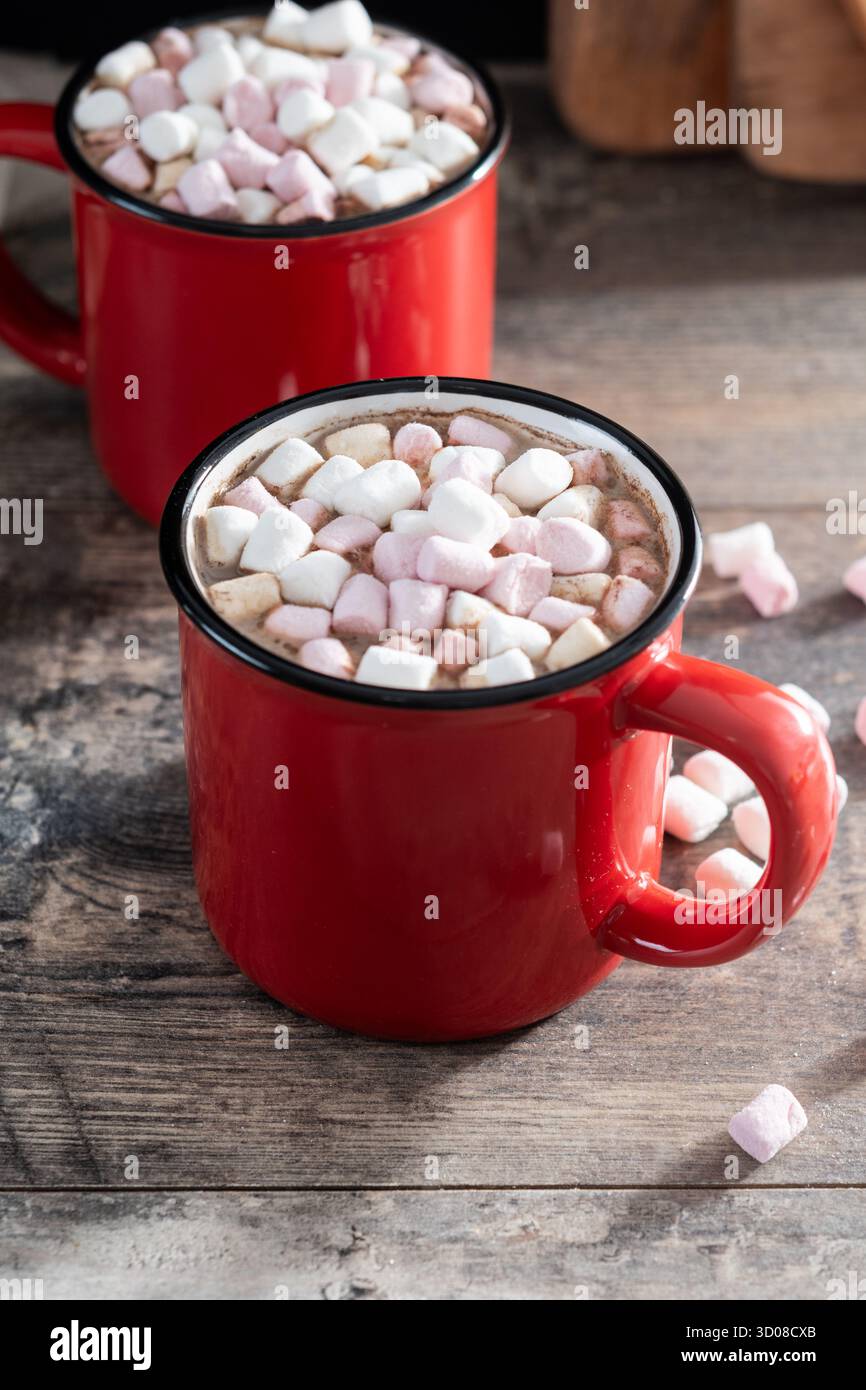 Bevanda calda a base di cioccolata con marshmallow in tazza rossa su un tavolo di legno Foto Stock