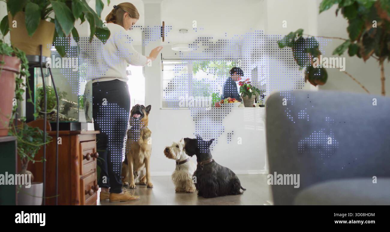 Donna adulta che guida tre cani nell'area soggiorno di casa, con piante in vaso, spazio per copiare Foto Stock