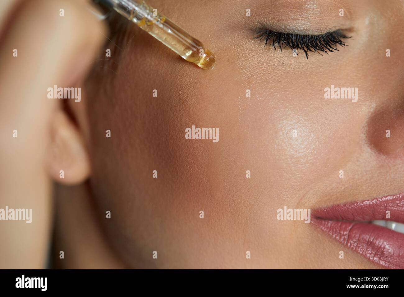 Siero. Idratante e nutriente. Primo piano ritratto di bellezza di una bella donna con pelle luminosa sta applicando un prodotto per la cura della pelle vitaminica c con un tubo Foto Stock