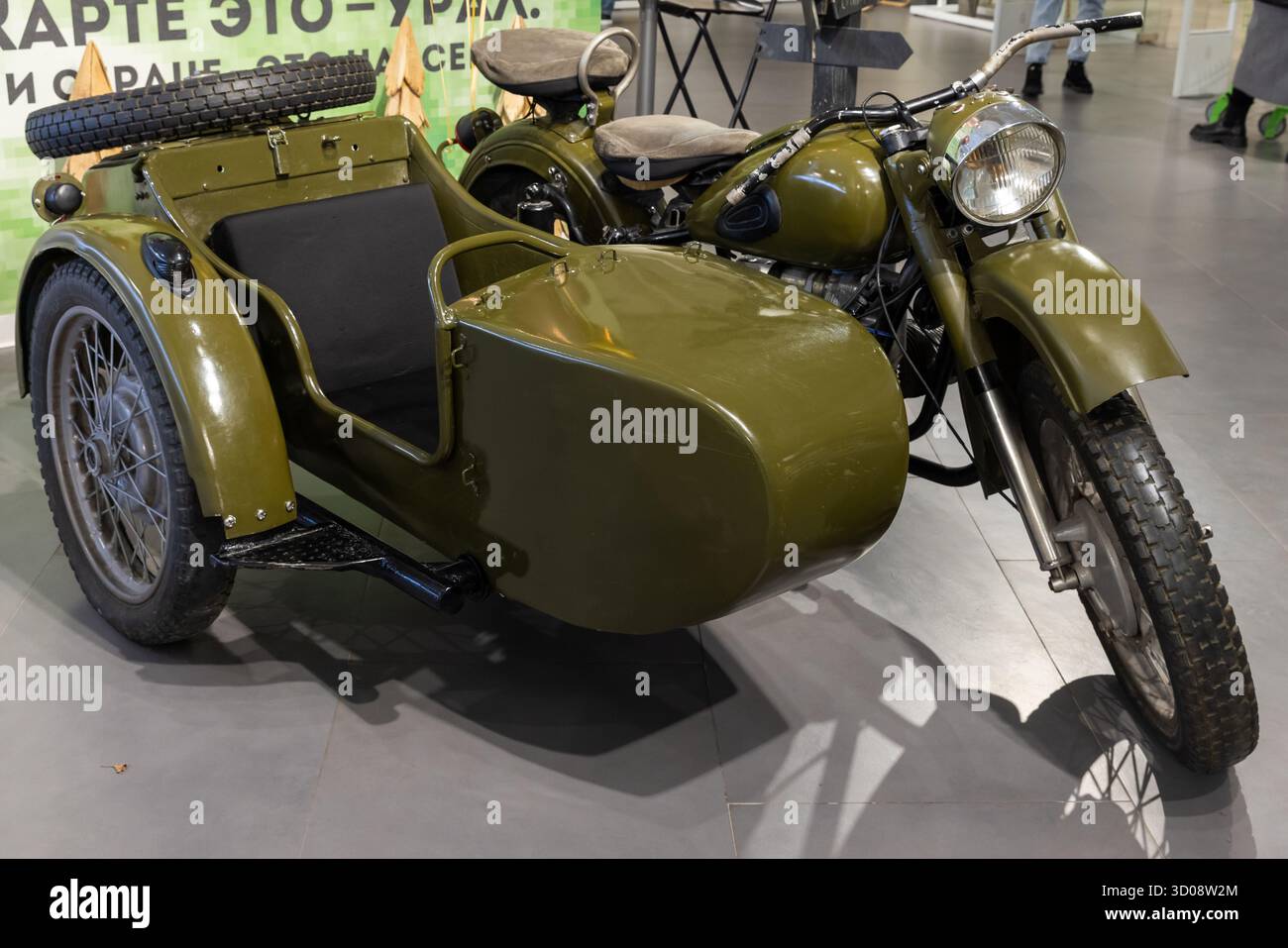Mosca, Russia - 1 dicembre 2024: Una motocicletta militare d'epoca verde oliva con sidecar abbinato in mostra in un moderno showroom. Design classico, Foto Stock