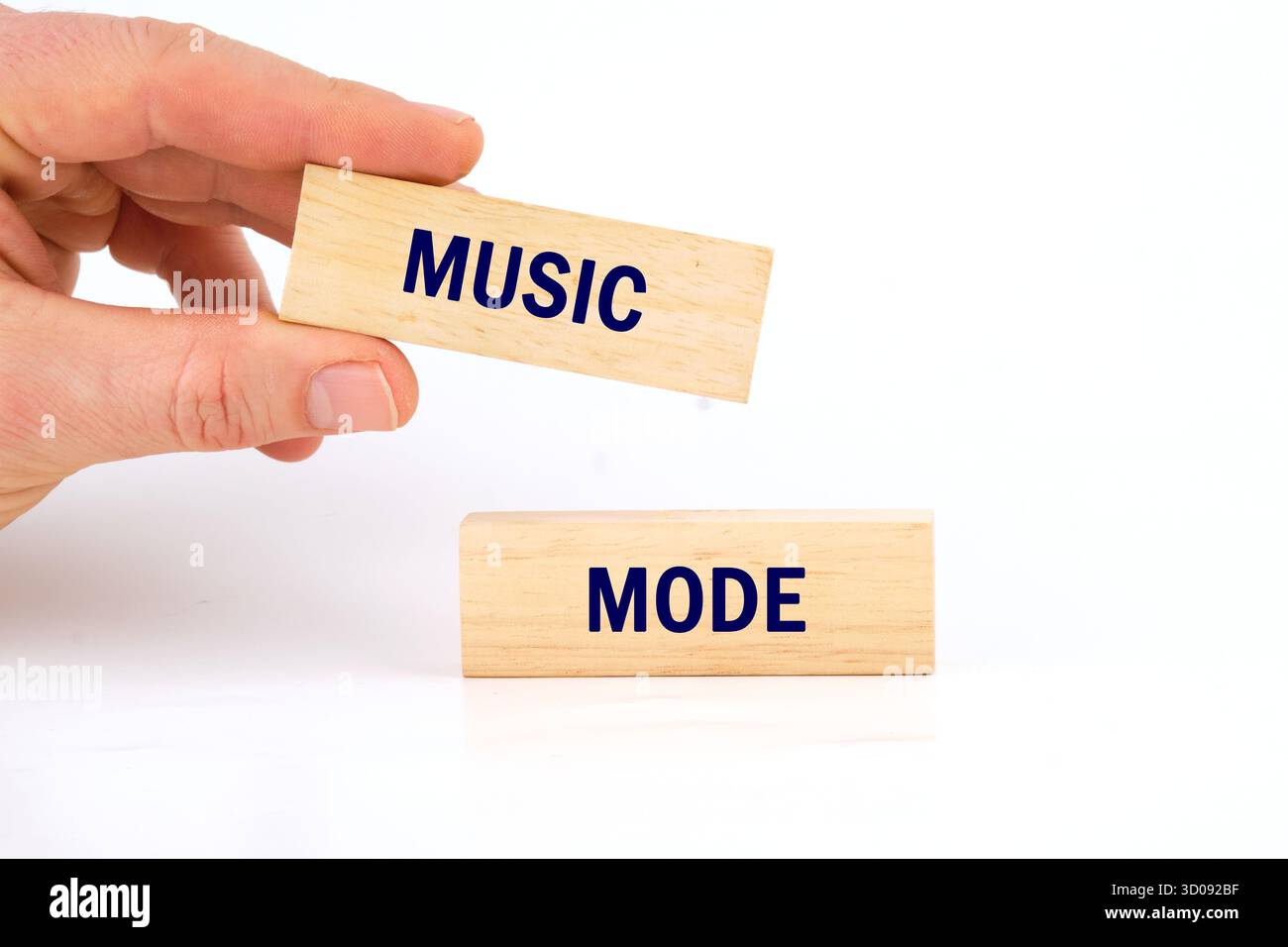 Una mano solleva delicatamente blocchi di legno che compongono musica e modalità. Questa scena simboleggia la creatività e il divertimento, ideale per attività coinvolgenti ed educ Foto Stock