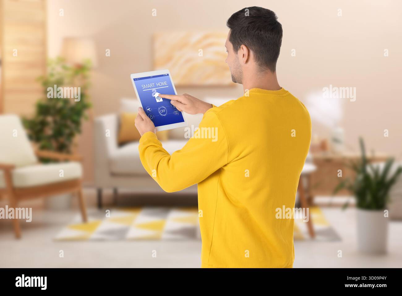 Uomo che utilizza un'app smart home su un tablet per controllare le funzionalità della casa Foto Stock