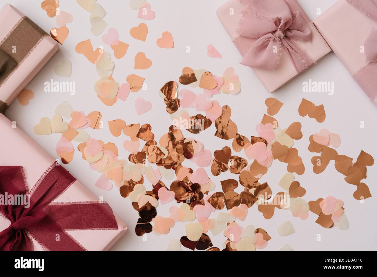 Composizione piatta con scatole regalo pastello e coriandoli a forma di cuore in tonalità rosa, pesca e oro. Un'estetica romantica da festeggiare. Foto Stock