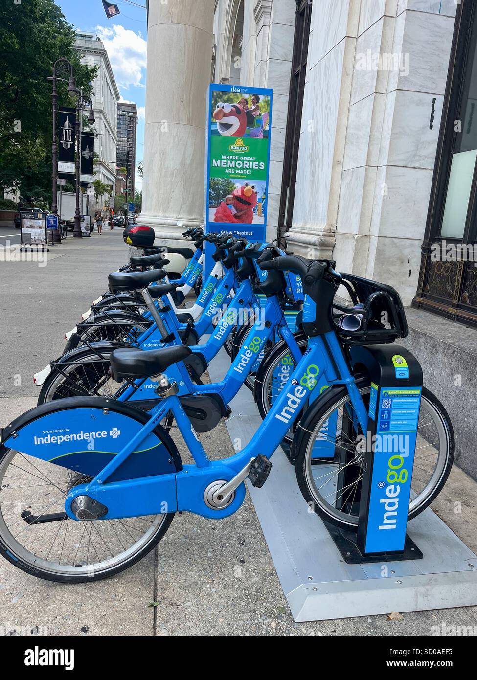 Una fila di bici blu Indego sono parcheggiate su un marciapiede. Le moto sono incatenate a un palo metallico Foto Stock Una fila di bici blu Indego sono parcheggiate su un marciapiede. Le moto sono incatenate a un palo metallico Foto Stock
