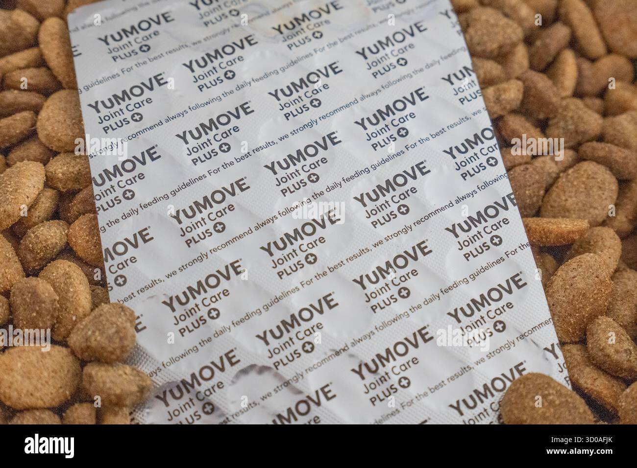 Contenitore pieno di kibble secco di cane dalle unghie e striscia di compresse YouMove insieme a una caraffa graduata Foto Stock